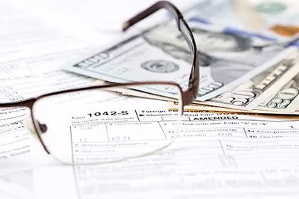 Glasses on tax forms and dollar bills.