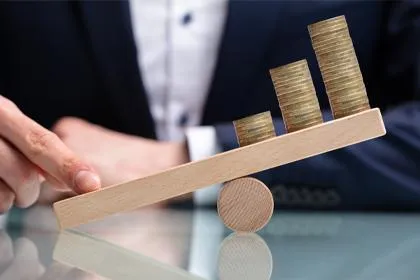 Balancing coins on wooden seesaw, business concept.