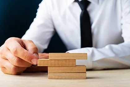 Person stacking wooden blocks on table.